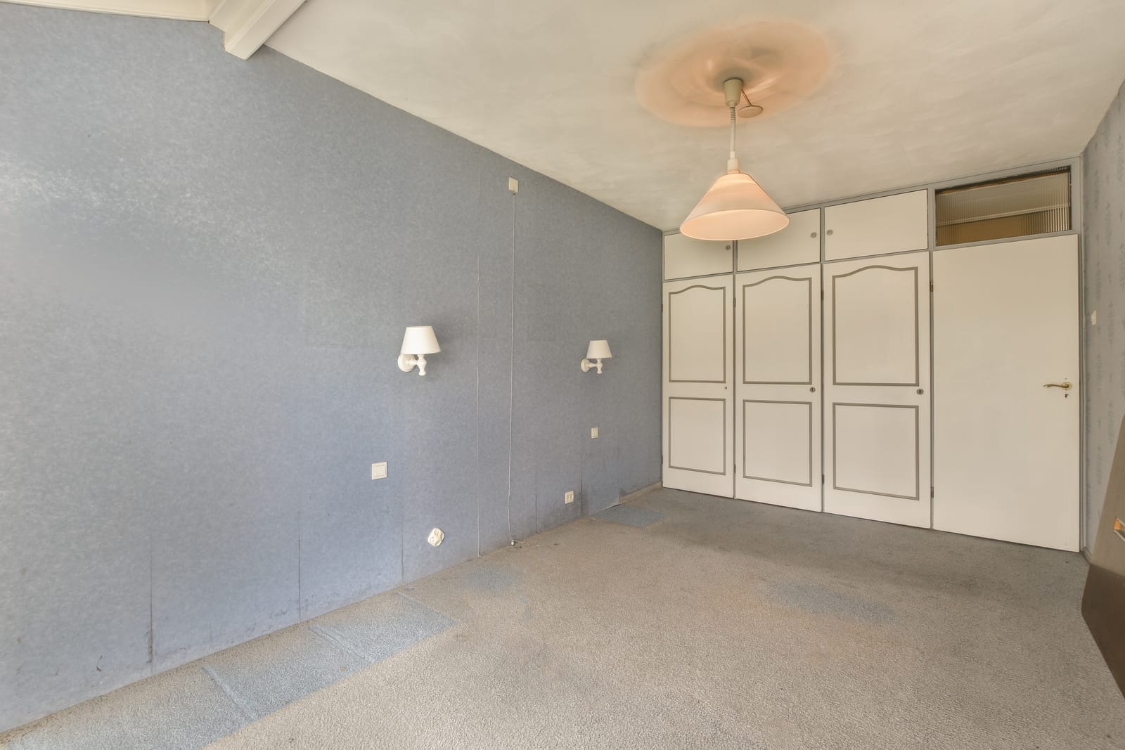 An Empty Room With White Doors And A Ceiling Lamp