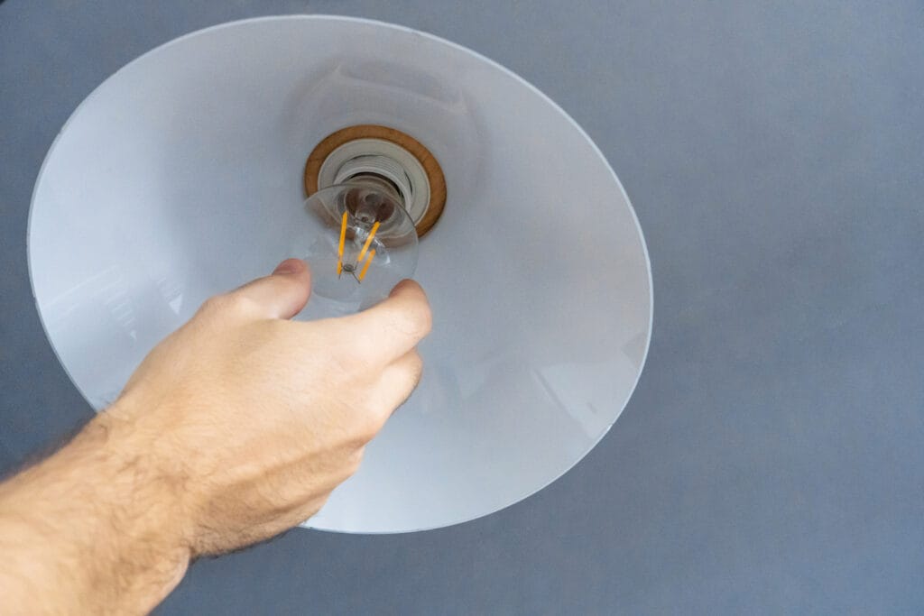 Close-Up. A Hand Changes A Light Bulb In A Stylish Loft Lamp. Spiral Filament Lamp. Modern Interior Decor