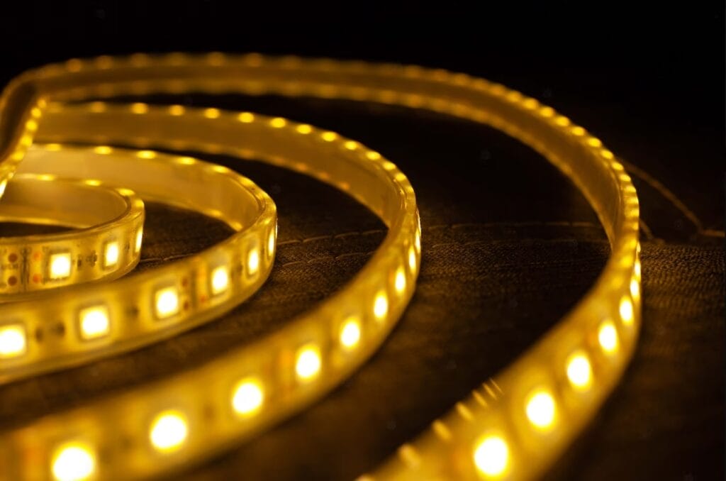 A roll of Yellow-colored LED Strips, gowing as its placed on a surface.