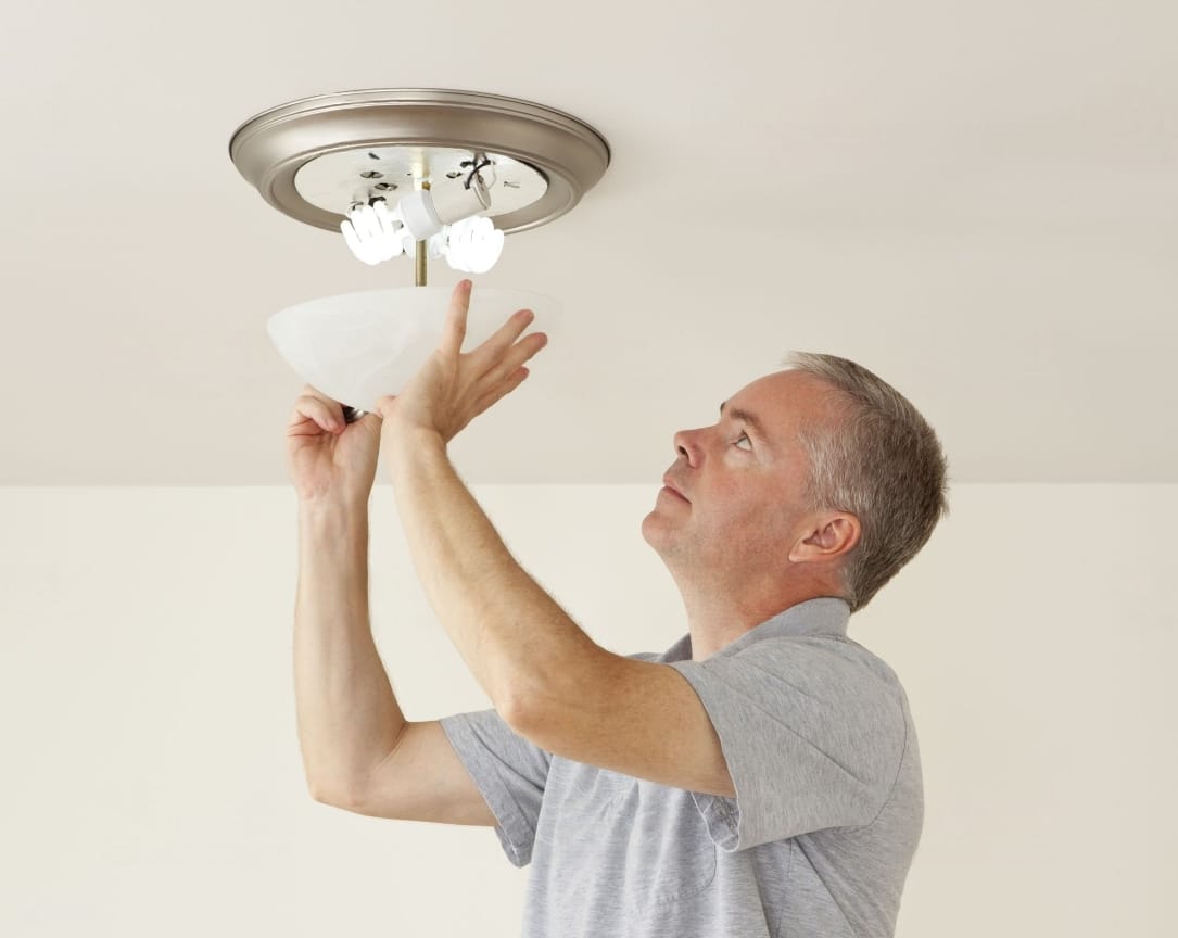A man removing the Light fixture cover with clips.