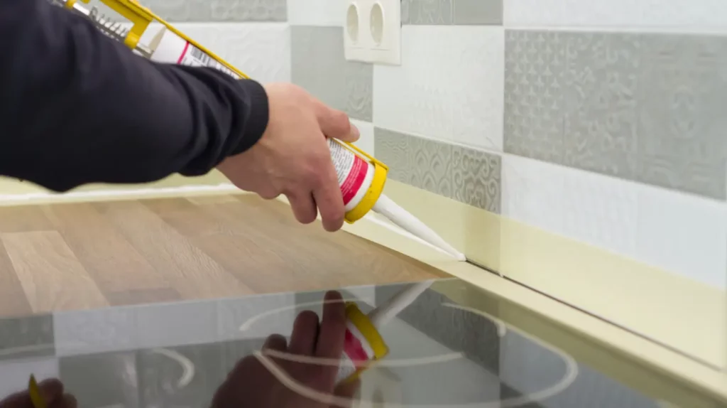 Silicone Caulk being applied on a corner near a stove.